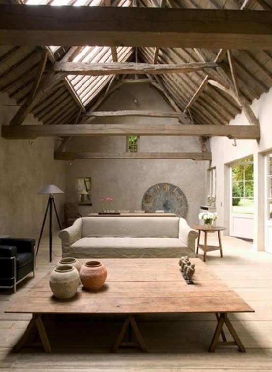 a cozy living room with a wabi-sabi feel - rough concrete walls, a wooden roof and beams