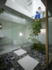 a contemporary Japanese courtyard with pebbles, stone tiles and a single tree growing