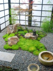 a Japanese courtyard with pebbles, rocks, stone bowls, a lantern and greenery around