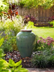 a delicate fountain of a planter is a unique idea for a zen garden, with blooms, greenery and rocks around