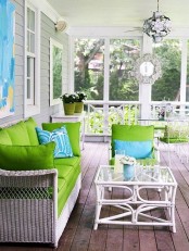 a bright and fresh summer porch with white wicker furniture, bright green and blue textiles and a white rattan coffee table