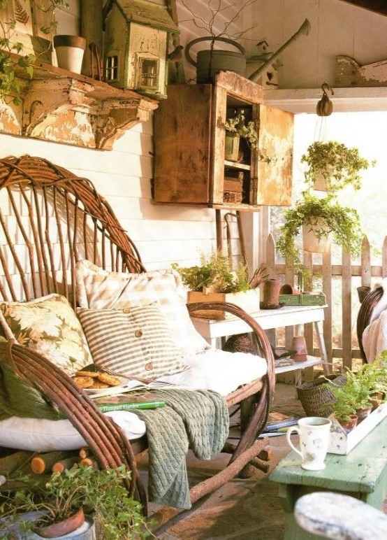 a rustic summer porch with wooden and rattan furniture, shabby chic cabinets and potted greenery