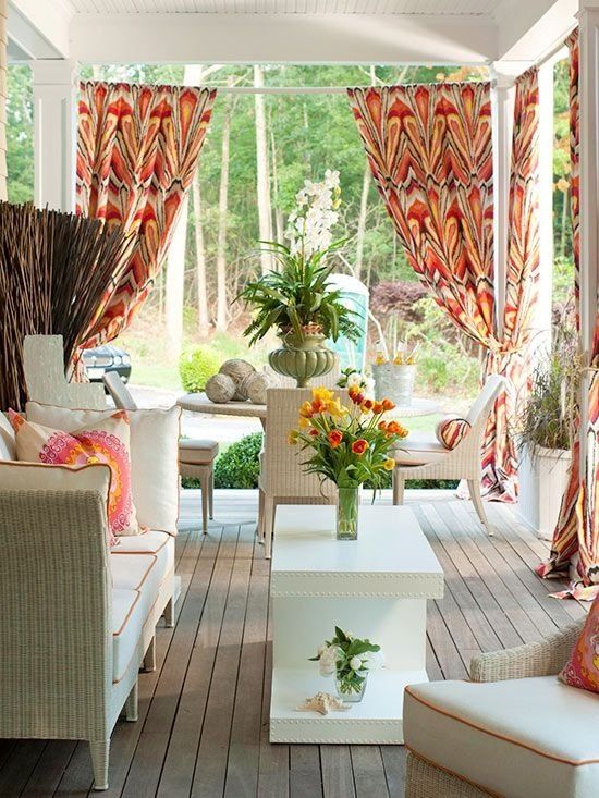 a cheerful summer porch with whiet wicker furniture, colorful pillows and curtains, a living and dining zone