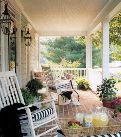 simple summer porch decor with white chairs with striped cushions, potted greenery and blooms, a basket for storage