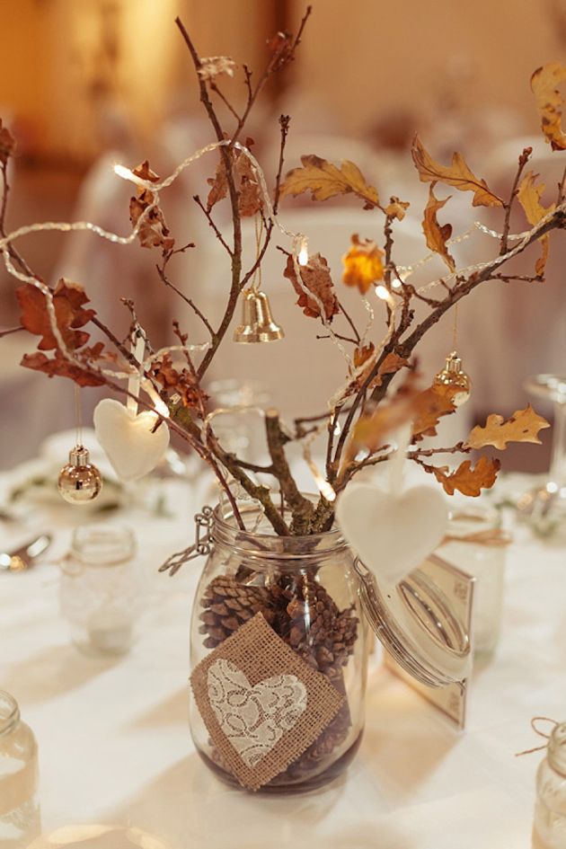 A jar with pinecones, branches with leaves, bells, lights and hearts as a creative fall decoration