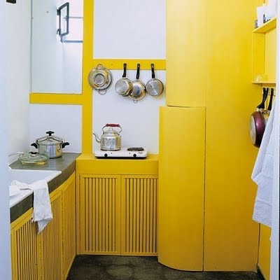 a lemon yellow kitchen with large white tiles and a concrete floor has a fresh feel and a very bold look