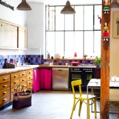 a loft kitchen with vintage cabinets, a colorful tile backsplasj, bold touches and textiles is cool and bright