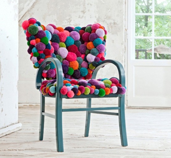 A blue chair fully covered with colorful pompoms is a gorgeous piece to sit on   it's cozy, warm and bright
