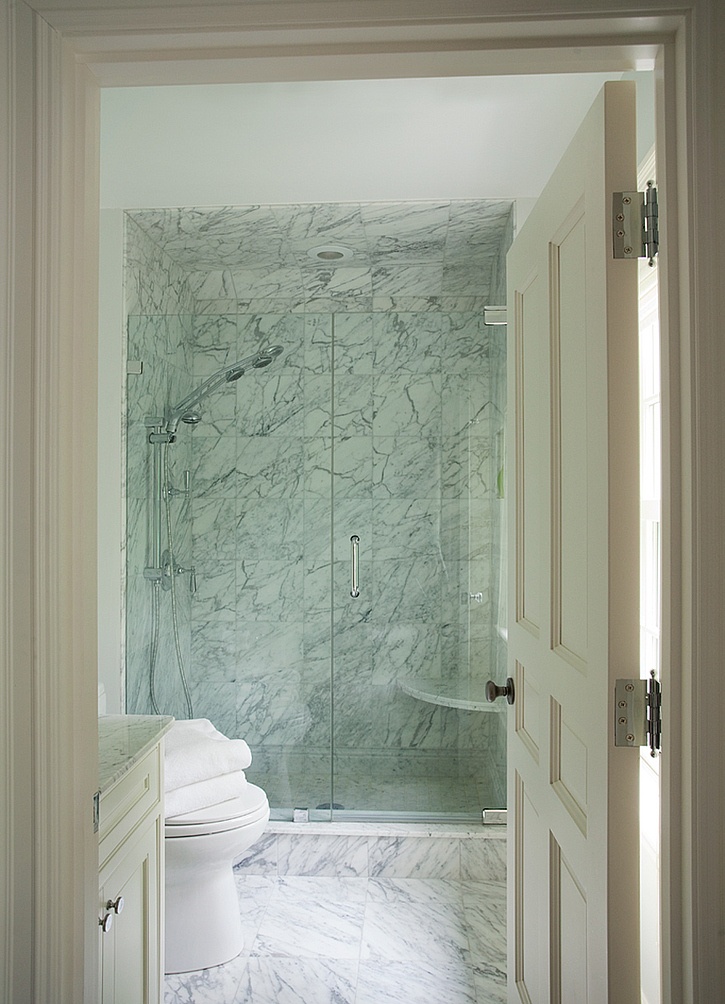 A laconic white marble bathroom with a shower space and a vanity   you won't need more than that