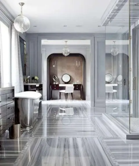 a vintagegrey bathroom with a grey marble floor, a shower space, a metallic tub and a vanity next to one wall