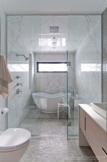 a marble bathroom with a shower space done with marble and tiles, a sleek vanity, seamless glass shower doors