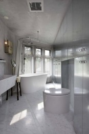 an unusual white marble bathroom done with metal panels, an oval tub and a sculptural sink of marble