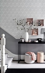 an airy entryway with grey walls and paneling, a black console table, pink box shelves and pink decor touches