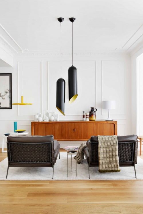 an elegant interior done with brown leather chairs, a small side table, a stained cabinet and catchy black pendant lamps