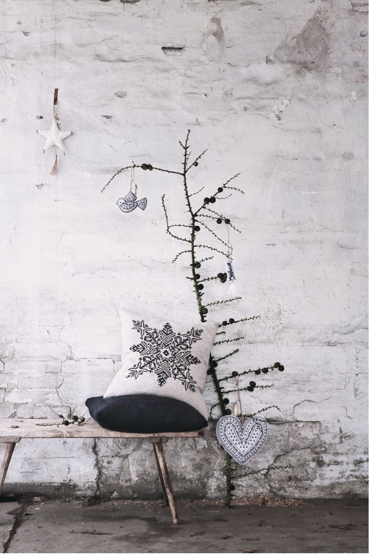A dried branch with pinecones and two fabric ornaments   a bird and a heart for a minimal Nordic look