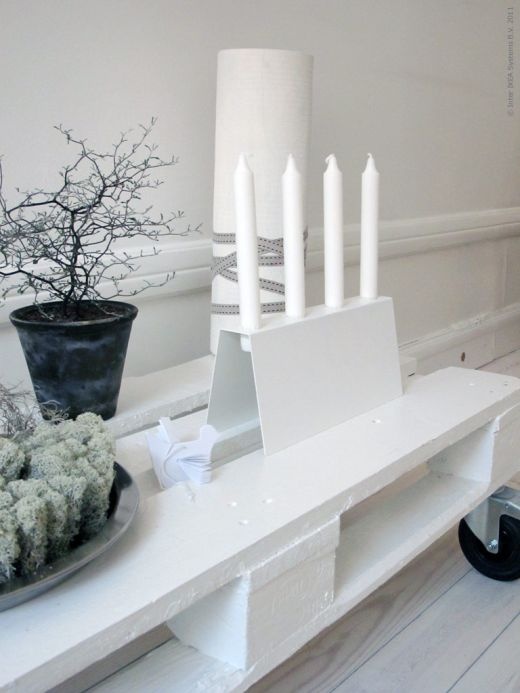 White candles in a white candle holder, black branches in a pot and some moss for an ultra minimal holiday look