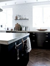 a Scandinavian kitchen with black cabinets, a white tile backsplash and concrete countertops looks ultra-modern and very fresh