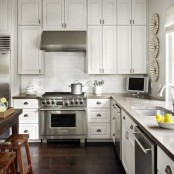 a simple white kitchen with concrete countertops, a white tile backsplash and lots of natural light incoming