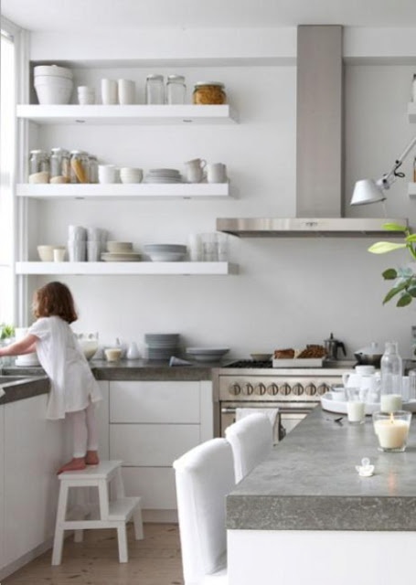 A white minimalist kitchen with concrete countertops and stainless steel appliances looks ultra modern and very laconic