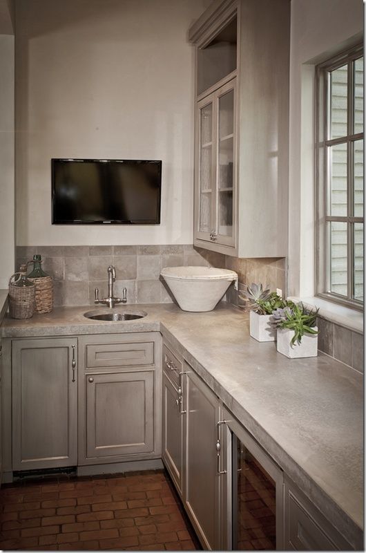 a grey farmhouse kitchen with cool cabinets and refined candles and concrete countertops plus tiles on the backsplash