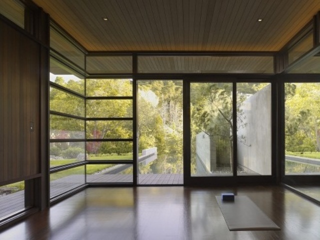a minimalist meditation room with glazed walls for much light and air and just some rugs