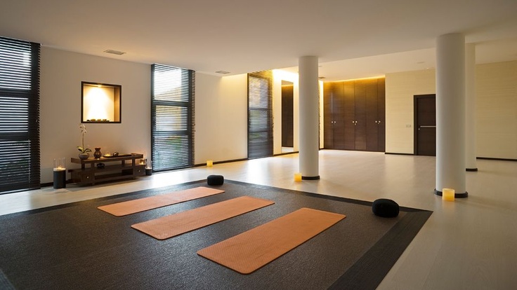 a minimalist meditation space with layered rugs, lamps and candles and large windows
