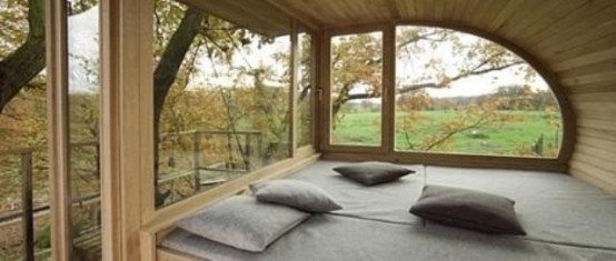 a contemporary meditation room with a catchy shape, glazed walls and an upholstered platform with cushions