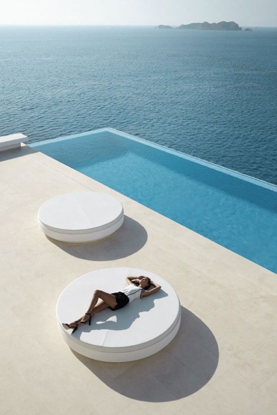 an ultra-minimalist terrace with a long and narrow pool, with white round beds and a fantastic sea view - who needs more than that