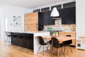a modern black and white kitchen with light-stained cabinets, a bright geo tile backsplash, an additional dining table attached to the kitchen island