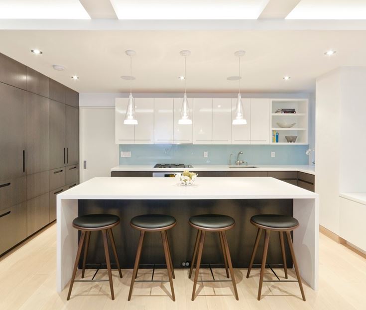 A modern white and graphite grey kitchen with a blue kitchen backsplash and a large kitchen island that features an eating space
