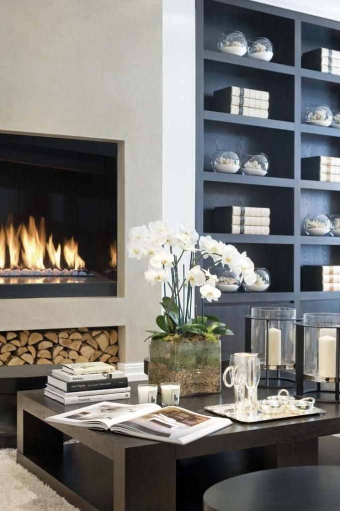 A chic modern living room with a built in fireplace and built in bookshelves, a low coffee table, a built in firewood storage niche