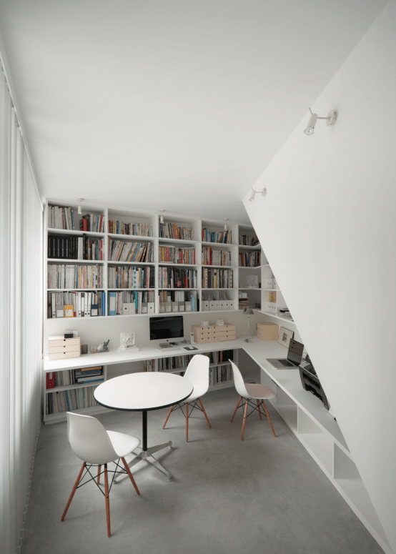a modern home office and library in one, with built-in bookshelves plus a built-in floating desk and chairs