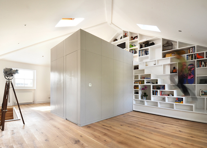 A modern home library with built in bookshelves placed on the wall and reaching the ceiling