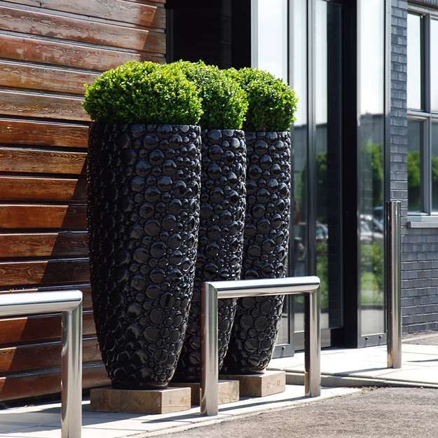 Ultra modern tall black planters with a bubble pattern are chic and bold decorations to rock for outdoors