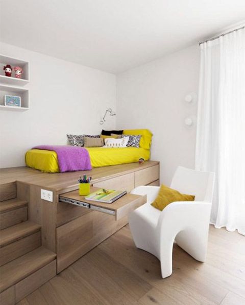 a modern teen bedroom with a bed on a platform that contains drawers and a desk plus a white curved chair