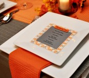 a modern colorful Thanksgiving tablescape in grey and orange, with square plates, a grey card and a bright orange runner and napkins