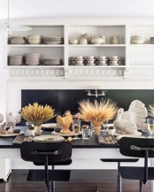 a stylish modern Thanksgiving tablescape with taupe napkins and table runners, wheat in vases, turkeys, candles and gold cutlery