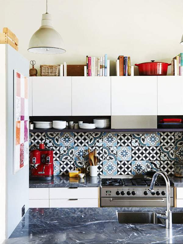 A modern to Scandi kitchen with sleek white cabinets, a bold blue and black Moroccan pattern tile backsplash and black stone countertops