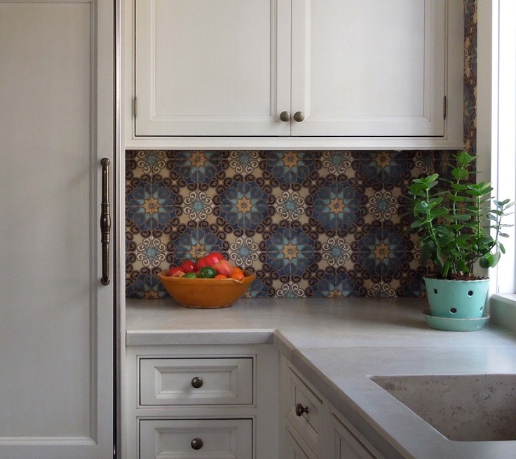 A modern neutral kitchen with shaker style cabinets and black knobs, with a colorful Moroccan pattern tile backsplash that adds interest and eye catchiness to the space