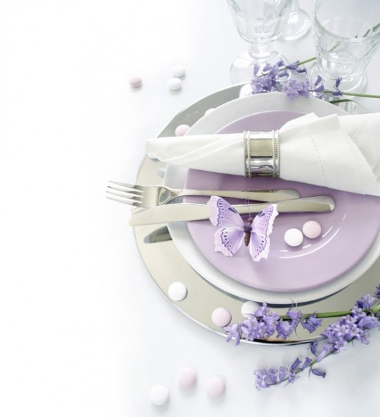 a pastel Mother's Day place setting with a metallic charger, lilac and white plates, a neutral napkin and some blooms