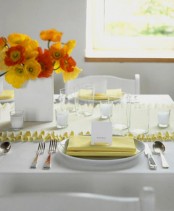 a bright Mother’s Day tablescape with a yellow runner, napkin and bold yellow and orange blooms and everything else styled in white