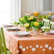 a colorful Mother’s Day tablescape with an orange tablecloth, greenery and yellow blooms, white porcelain is a cute and fun solution