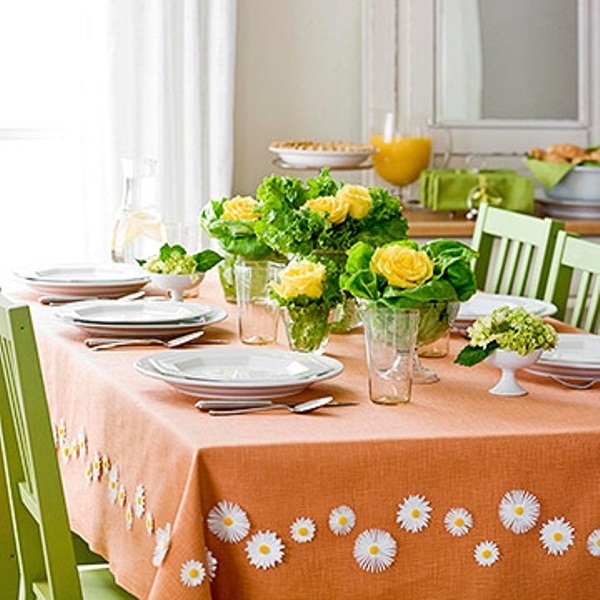 A colorful Mother's Day tablescape with an orange tablecloth, greenery and yellow blooms, white porcelain is a cute and fun solution
