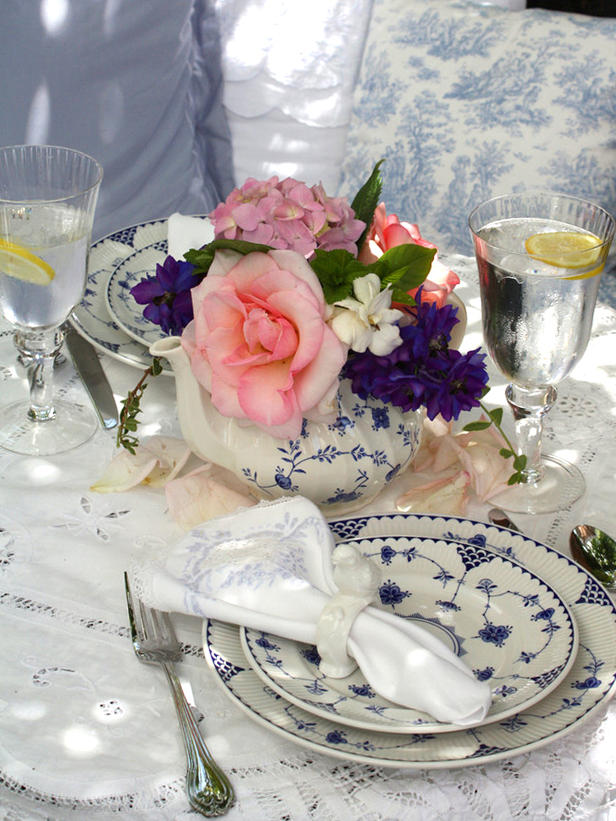 Elegant vintage inspired wedding tablescape with a lace tablecloth. bright blooms, blue printed porcelain and gold rimmed glasses