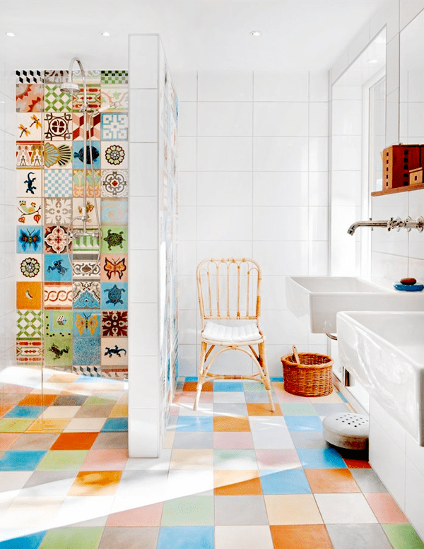 A bright multi color tiled bathroom with just colorful and printed tiles in the shower, with white appliances to create a balance