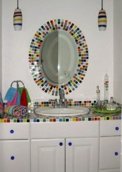 a white bathroom accented with super bright and colorful tiles on the vanity and mirror frame is a great idea for a kid’s bathroom