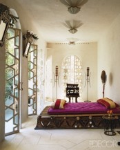 a neutral Moroccan bedroom with a star printed floor, ornate mirrors and lamps and a unique carved platform bed