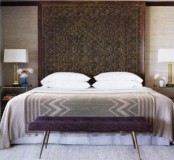 a Moroccan feel is given with a rug on the wall, printed bedding and a purple bench at the foot of the bed