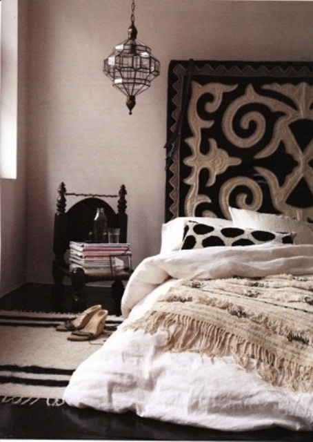 a monochromatic Moroccan living room with a patterned rug, a lantern, a carved chair and a Moroccan wedding blanket