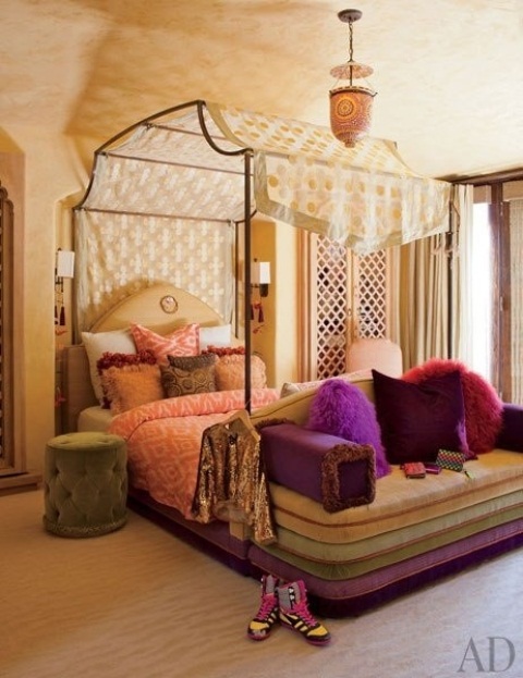 a bright Moroccan bedroom with a whimsy bed with a unique canopy and super bright bedding and a velvet upholstered bench